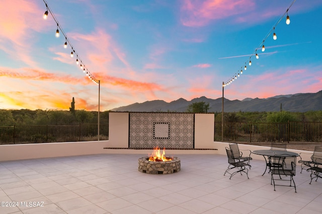 view of patio / terrace featuring an outdoor fire pit, fence, and a mountain view