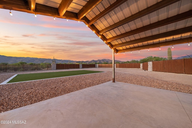 patio terrace at dusk featuring a fenced backyard and a mountain view