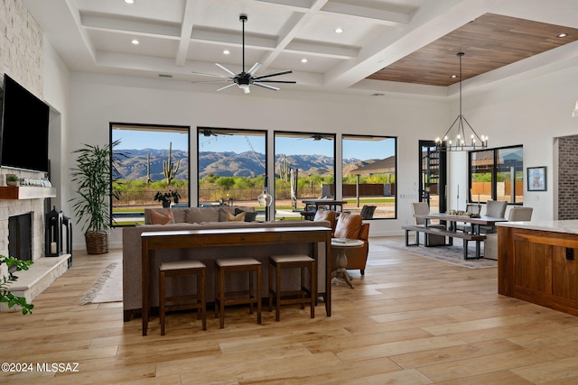 interior space featuring a fireplace, a high ceiling, open floor plan, a mountain view, and light wood-type flooring