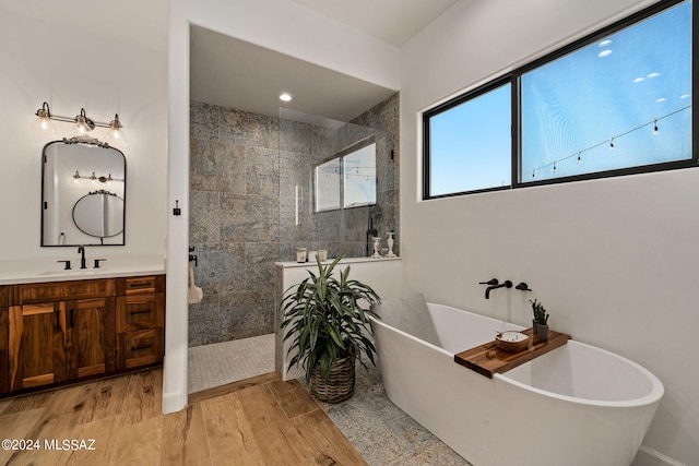 bathroom with wood finished floors, a freestanding tub, walk in shower, and vanity