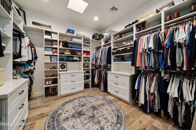 walk in closet featuring light wood-type flooring, a skylight, and visible vents