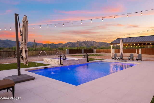 pool at dusk with a fenced backyard, a mountain view, and a patio