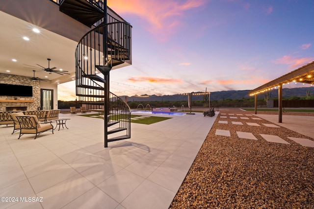 exterior space with ceiling fan, a mountain view, an outdoor stone fireplace, stairs, and an outdoor pool