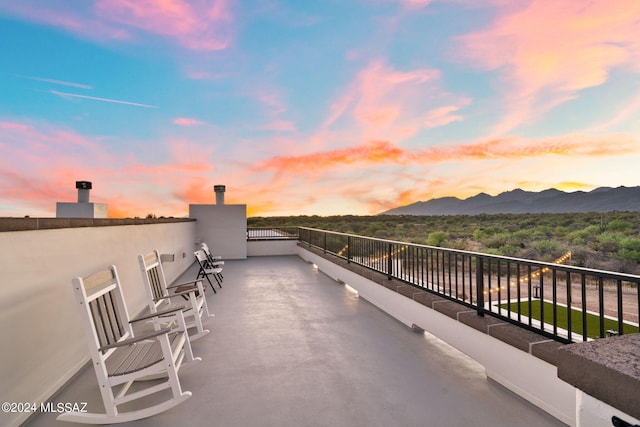 patio terrace at dusk featuring a mountain view and a balcony