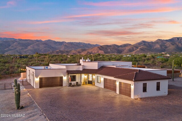 view of front of home featuring stucco siding, an attached garage, fence, a mountain view, and driveway