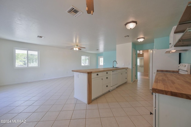 kitchen featuring kitchen peninsula, light tile patterned floors, white cabinets, wood counters, and dishwasher