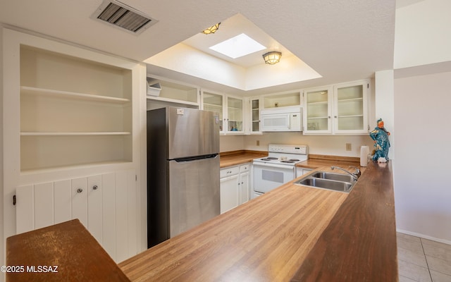 kitchen with visible vents, a sink, wooden counters, white appliances, and a skylight