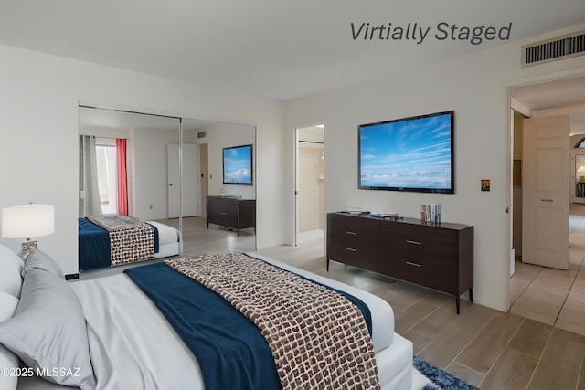 bedroom featuring visible vents, baseboards, a closet, light wood-style floors, and connected bathroom