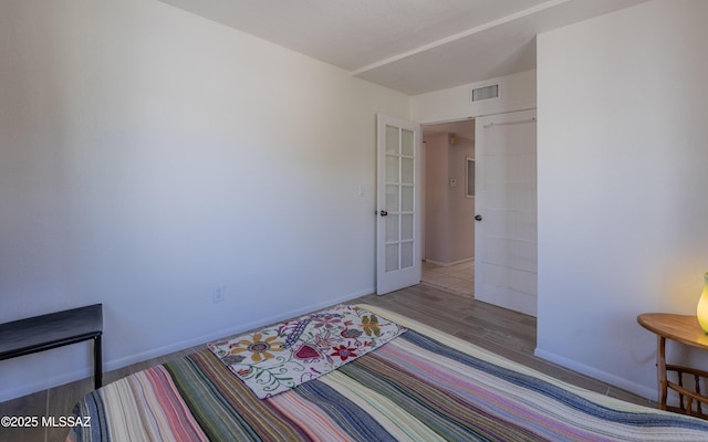 bedroom with visible vents, french doors, baseboards, and wood finished floors