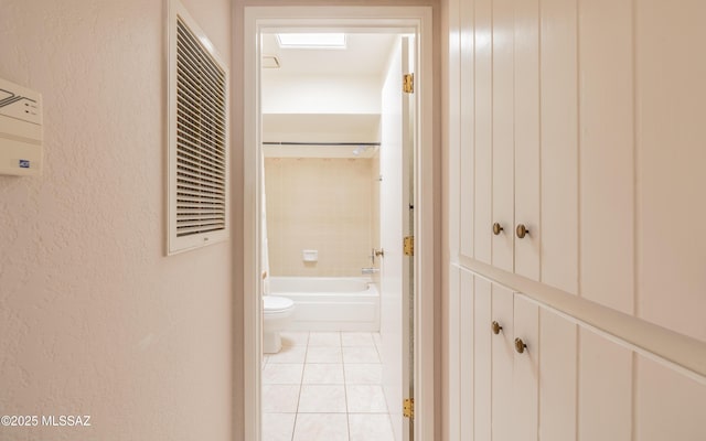 corridor with light tile patterned floors and a textured wall