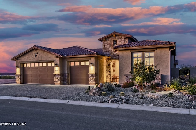 view of front of property featuring a garage, stone siding, decorative driveway, and stucco siding