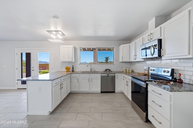 kitchen with kitchen peninsula, tasteful backsplash, appliances with stainless steel finishes, a notable chandelier, and white cabinets