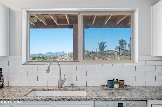 details with sink, light stone counters, tasteful backsplash, white cabinets, and a mountain view