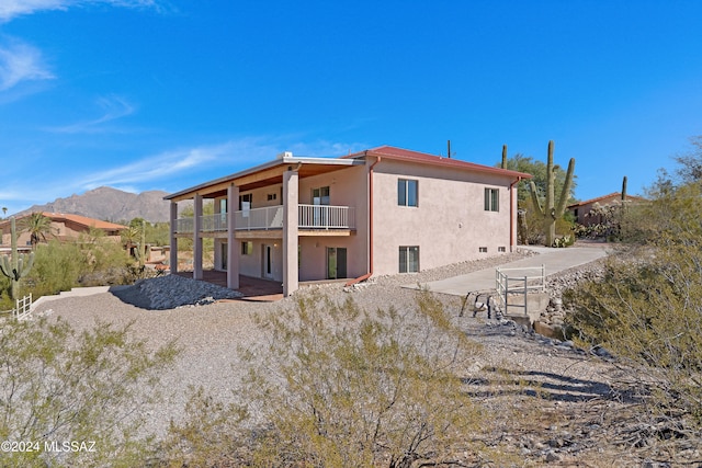 rear view of house with a patio, a mountain view, and a balcony