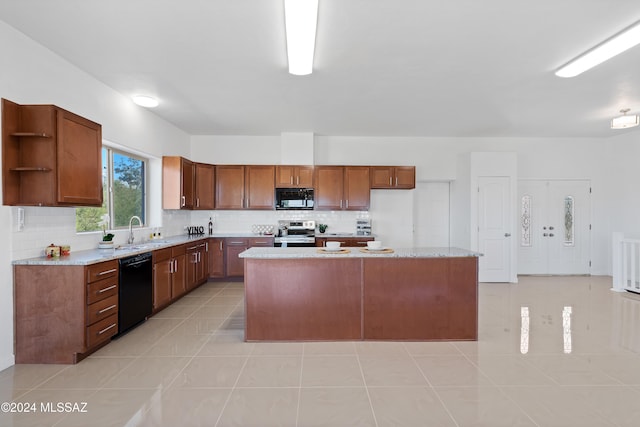 kitchen featuring black appliances, backsplash, light tile patterned floors, sink, and a center island