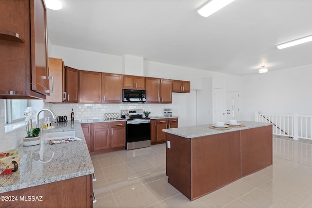 kitchen with backsplash, light stone countertops, sink, electric range, and a center island