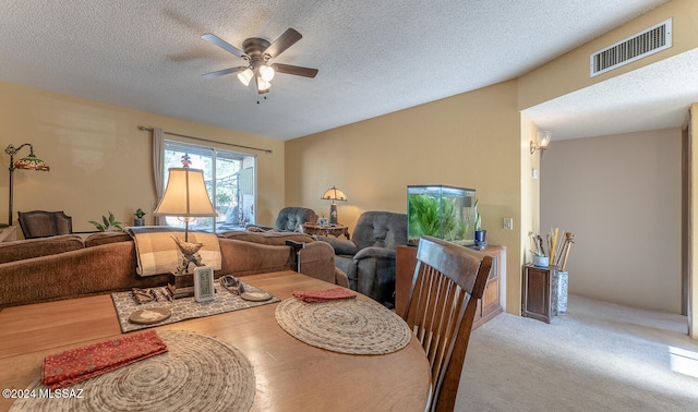 dining space featuring light carpet, a textured ceiling, and ceiling fan