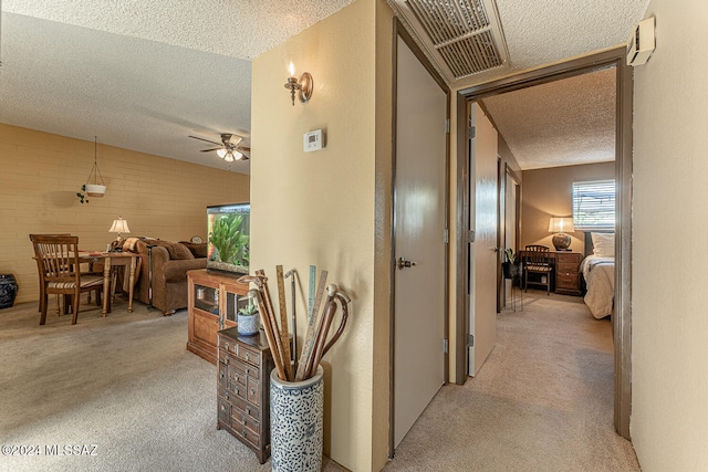 hallway with light carpet, a textured ceiling, and brick wall