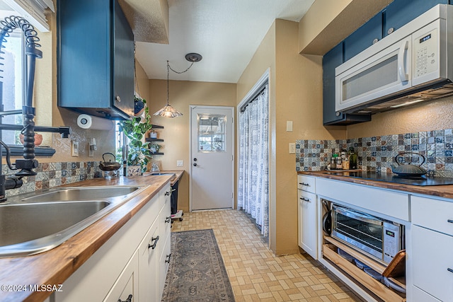 kitchen with blue cabinetry, white cabinetry, wooden counters, and decorative light fixtures