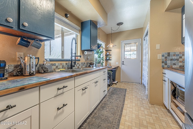 kitchen featuring white cabinets, a healthy amount of sunlight, sink, and hanging light fixtures