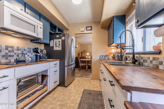 kitchen featuring sink, white cabinetry, stainless steel appliances, and wood counters