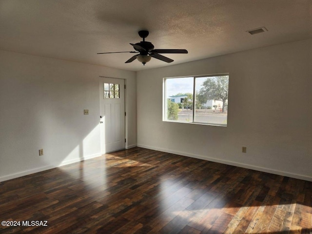 spare room featuring dark hardwood / wood-style floors, ceiling fan, and a textured ceiling