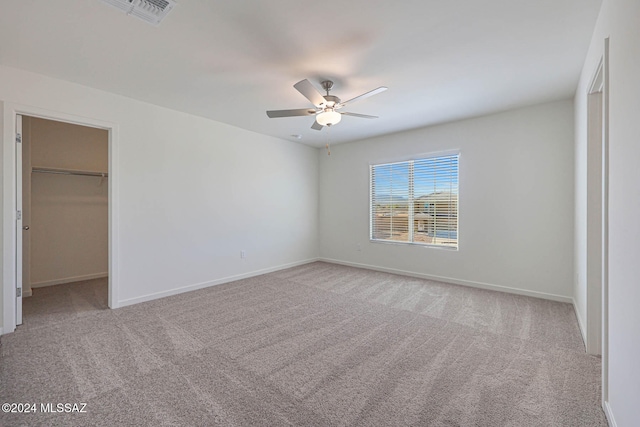 unfurnished bedroom featuring ceiling fan, a closet, a spacious closet, and light colored carpet