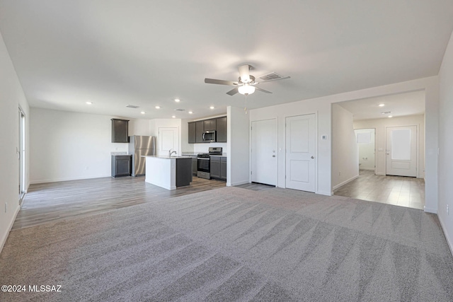 unfurnished living room with light hardwood / wood-style floors, sink, and ceiling fan