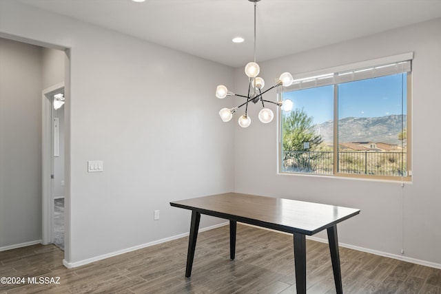 unfurnished dining area featuring dark wood-type flooring, a mountain view, and an inviting chandelier