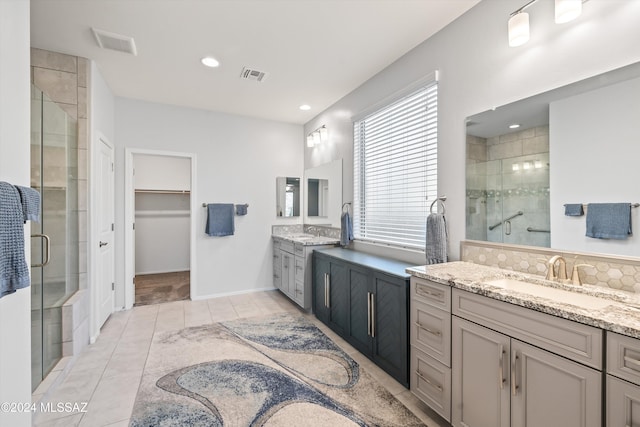 bathroom featuring vanity, a shower with door, tile patterned floors, and tasteful backsplash