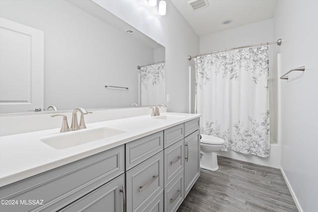 full bathroom featuring hardwood / wood-style floors, vanity, shower / bathtub combination with curtain, and toilet