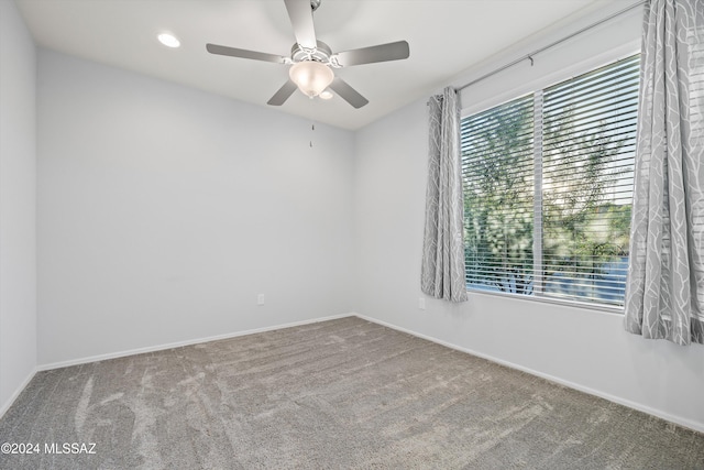 carpeted spare room with a wealth of natural light and ceiling fan