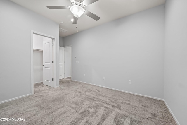 unfurnished bedroom with a spacious closet, light carpet, ceiling fan, and a closet