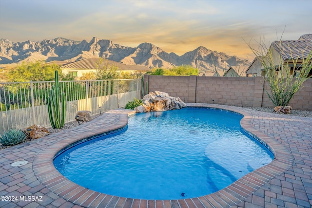 pool at dusk with a mountain view and pool water feature