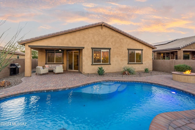 pool at dusk featuring a grill, ceiling fan, outdoor lounge area, and a patio