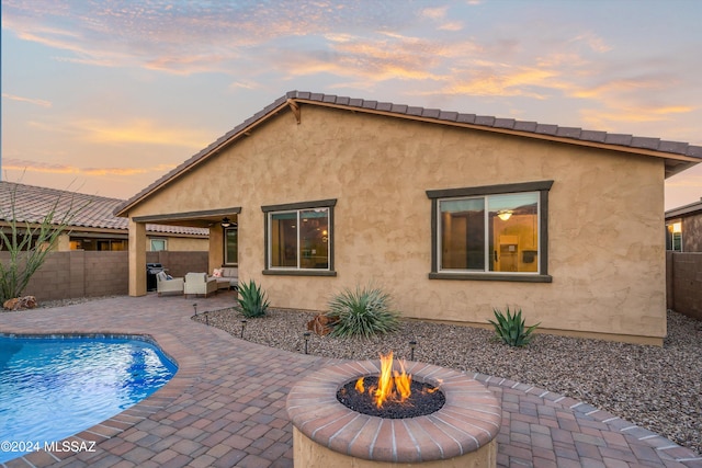 pool at dusk featuring a fire pit and a patio area