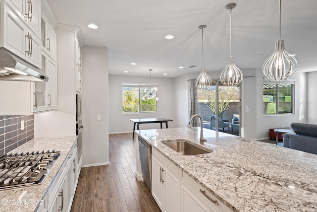 kitchen featuring white cabinets, sink, backsplash, pendant lighting, and appliances with stainless steel finishes