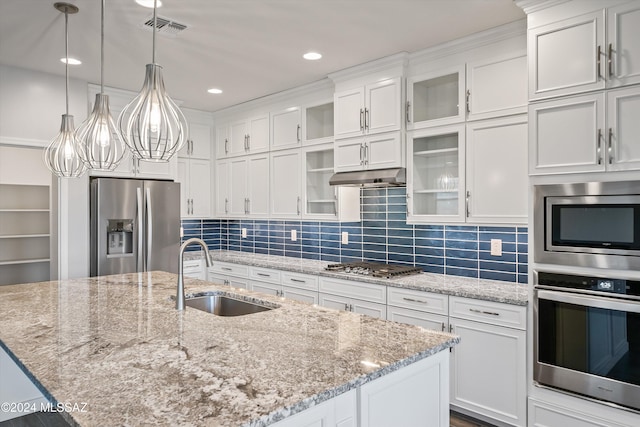 kitchen with a center island with sink, white cabinetry, appliances with stainless steel finishes, hanging light fixtures, and sink