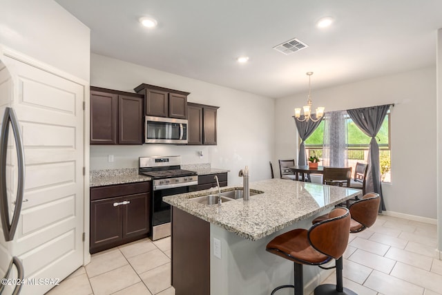 kitchen featuring stainless steel appliances, light stone counters, a notable chandelier, sink, and pendant lighting