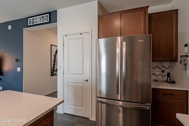 kitchen with dark tile patterned floors, stainless steel fridge, and decorative backsplash