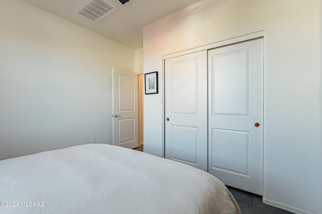 bedroom featuring dark tile patterned flooring and a closet