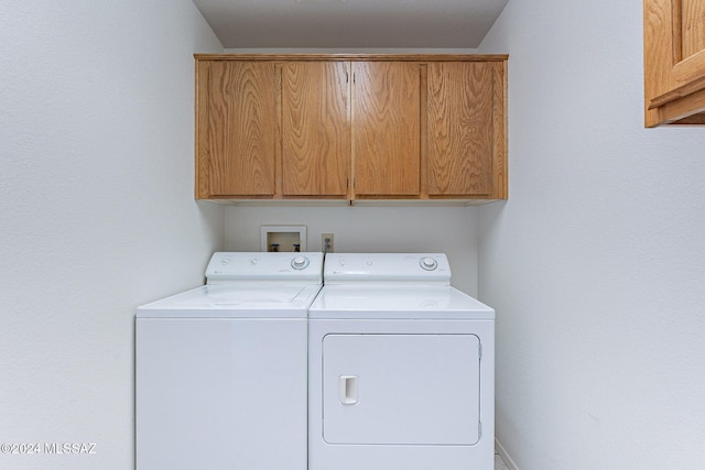 clothes washing area featuring independent washer and dryer and cabinets