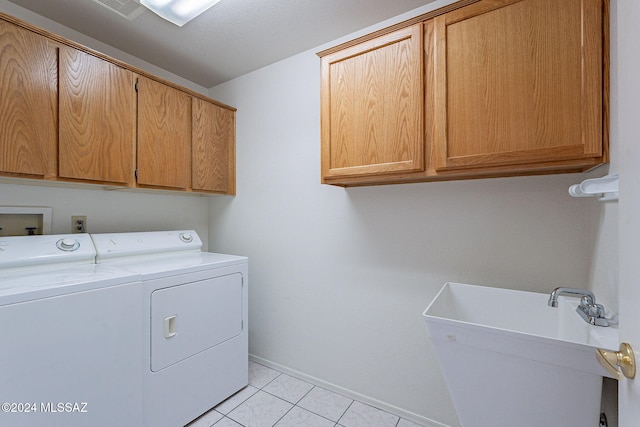 clothes washing area featuring sink, washer and clothes dryer, light tile patterned flooring, and cabinets