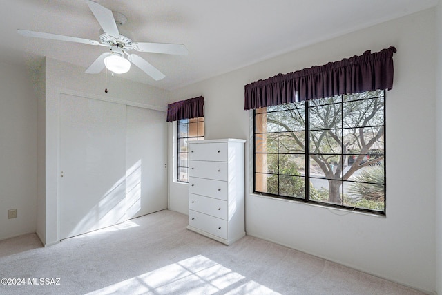 unfurnished bedroom featuring a closet, ceiling fan, light carpet, and multiple windows