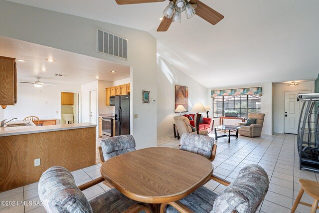 dining space featuring lofted ceiling, light tile patterned flooring, sink, and ceiling fan