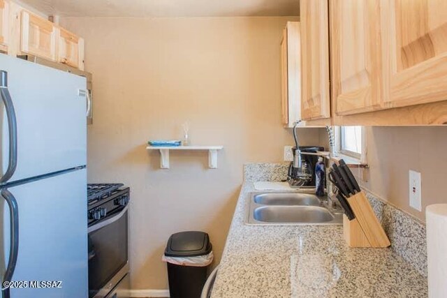 2112 E 18th St, Tucson, AZ 85719 - kitchen with white refrigerator, sink, light stone countertops, light brown cabinetry, and gas stove