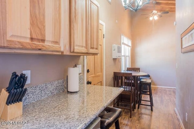 2112 E 18th St, Tucson, AZ 85719 - kitchen featuring light stone counters, hardwood / wood-style floors, a breakfast bar area, light brown cabinetry, and ceiling fan with notable chandelier