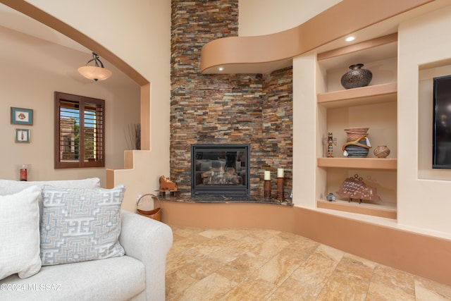 living room with built in features and a stone fireplace