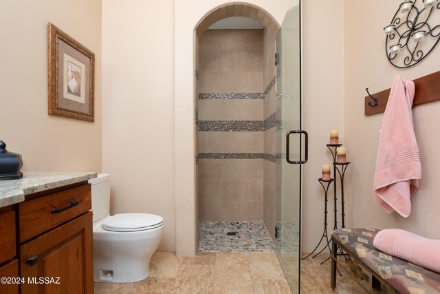 bathroom with vanity, toilet, and a shower with door