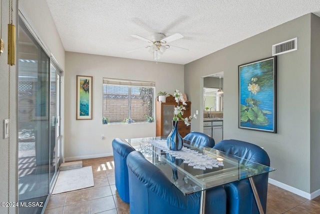 tiled dining space with sink, a textured ceiling, and ceiling fan